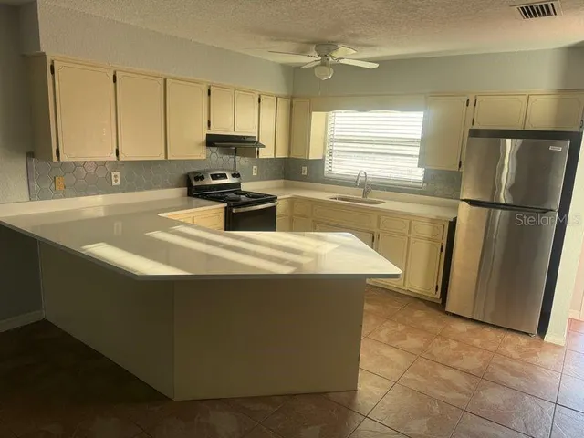 a kitchen with granite countertop a refrigerator a sink a stove a microwave a counter top and cabinets