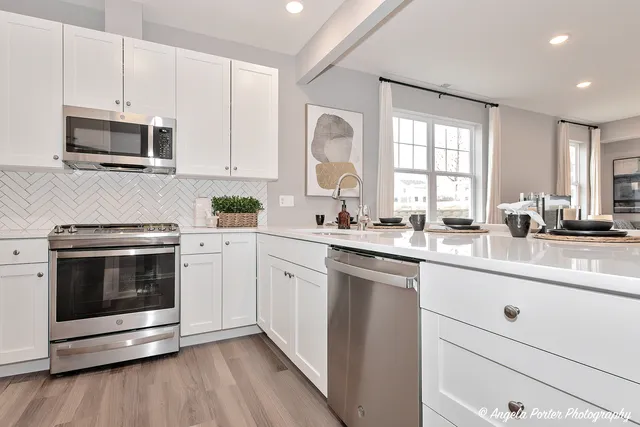 a kitchen with stainless steel appliances white cabinets a sink and a stove