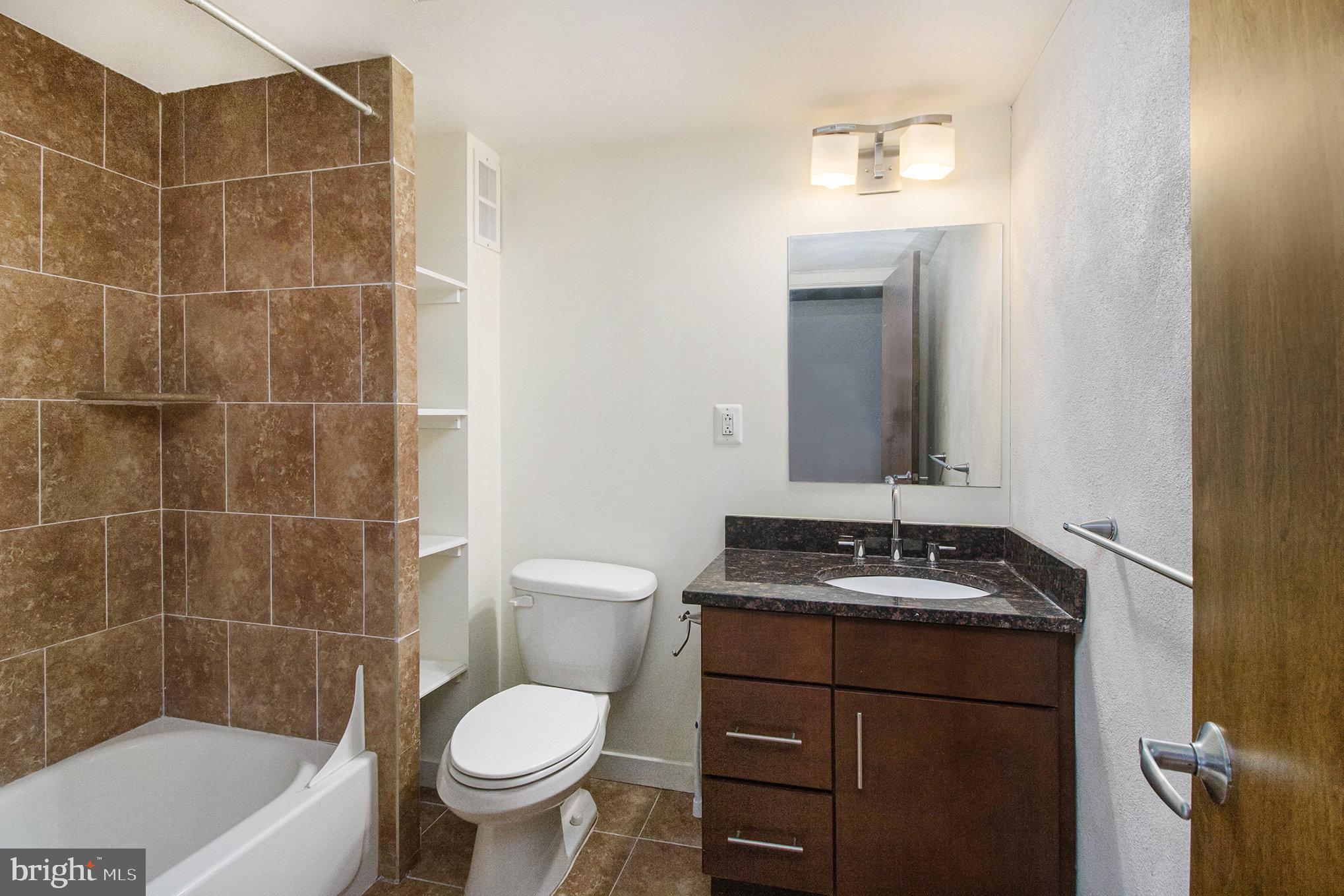 1201 Fitzwater Street, Unit 207 Philadelphia, PA 19147 - Photo 21 of 39 a bathroom with a granite countertop sink a toilet and mirror