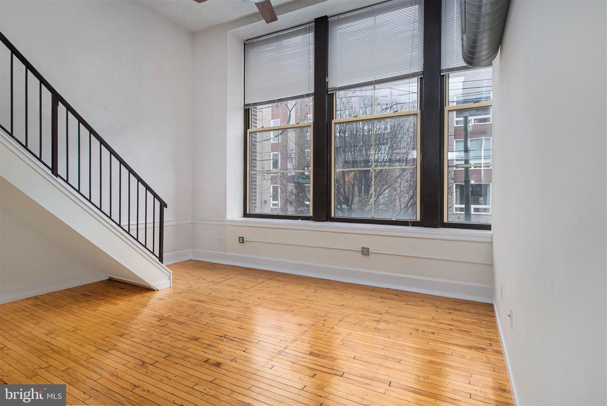 1201 Fitzwater Street, Unit 207 Philadelphia, PA 19147 - Photo 10 of 39 a view of an empty room with wooden floor and a window
