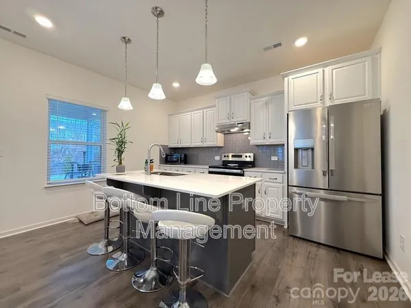 a kitchen with stainless steel appliances a table chairs refrigerator and microwave