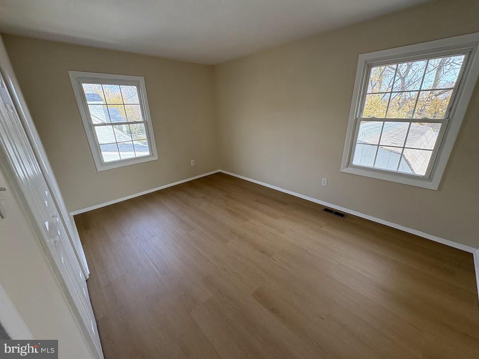 7907 Chalice Road Severn, MD 21144 - Photo 12 of 34 an empty room with wooden floor and windows