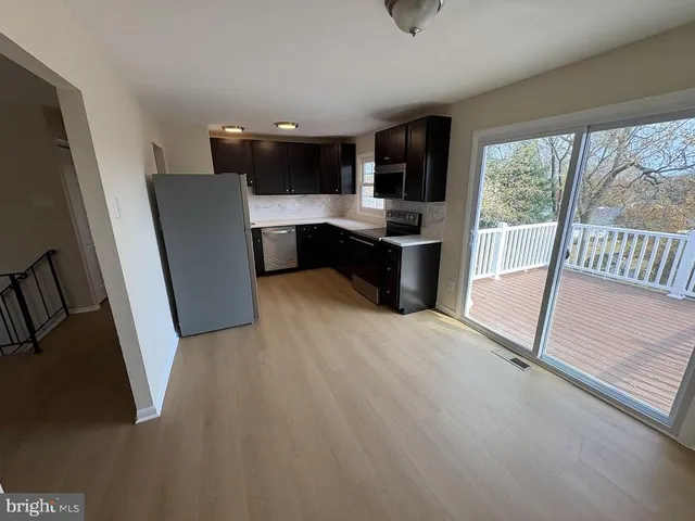 a view of kitchen with stainless steel appliances wooden floor and window