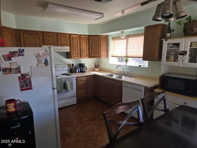 a kitchen with a sink a stove a refrigerator cabinets and a dining table