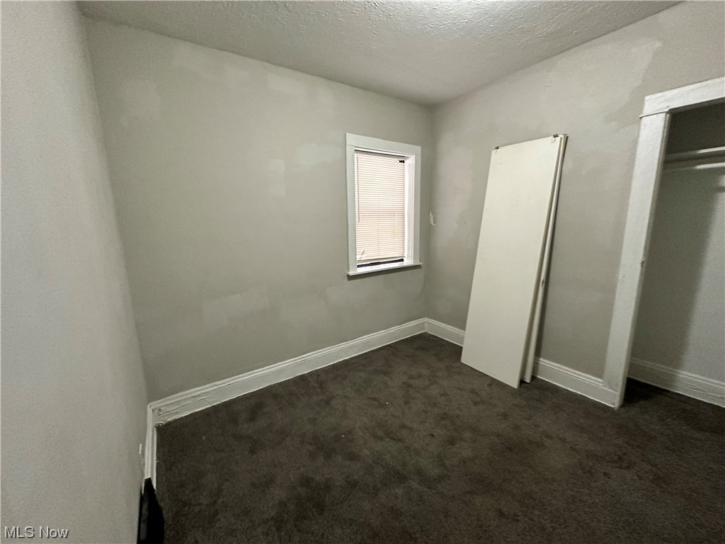6734 Ottawa Road Cleveland, OH 44105 - Photo 12 of 31 Unfurnished bedroom with dark carpet, a textured ceiling, and a closet