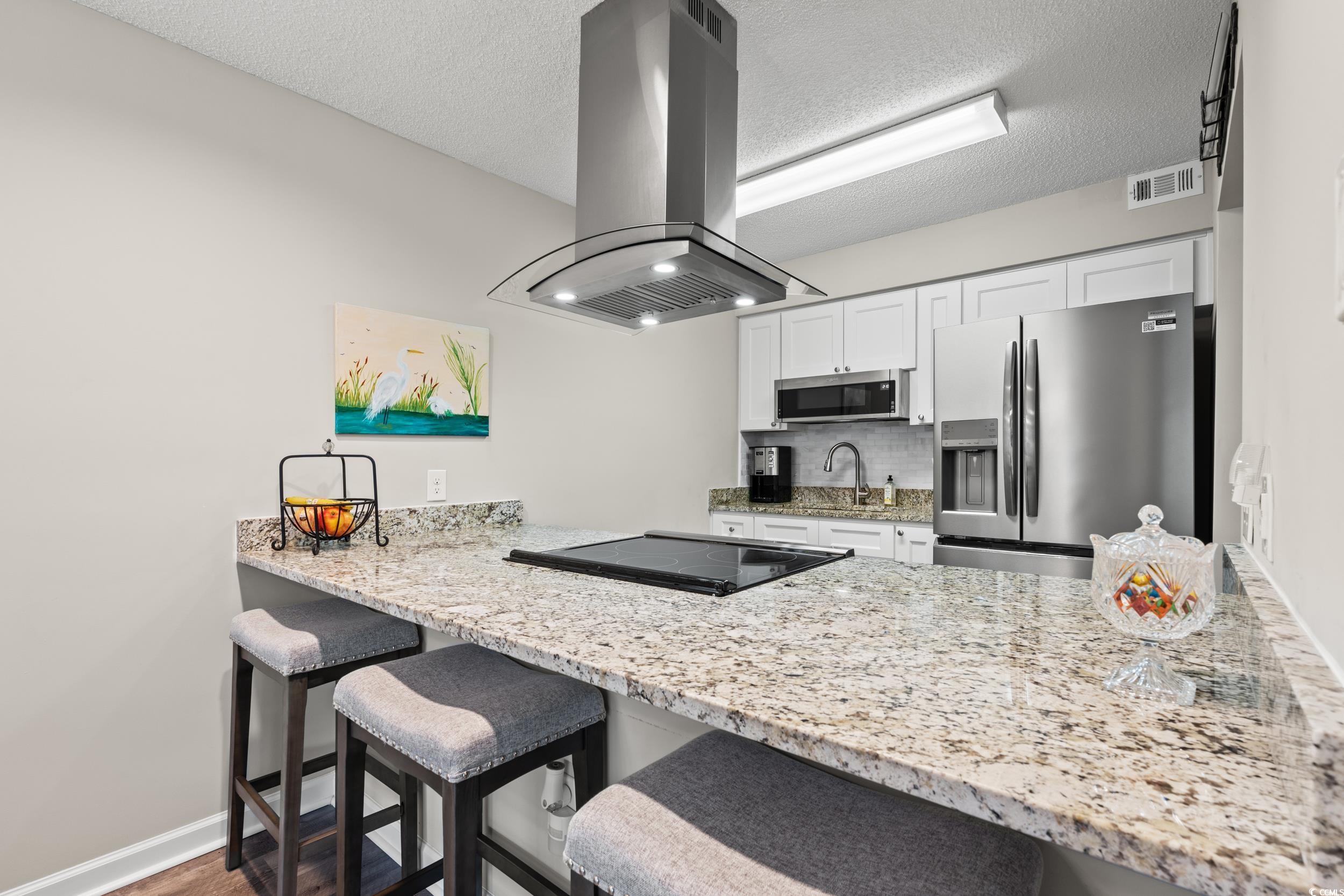 14 Laurel Street, Unit 14 Conway, SC 29526 - Photo 12 of 40 Kitchen with a peninsula, decorative backsplash, light stone counters, stainless steel appliances, and a textured ceiling