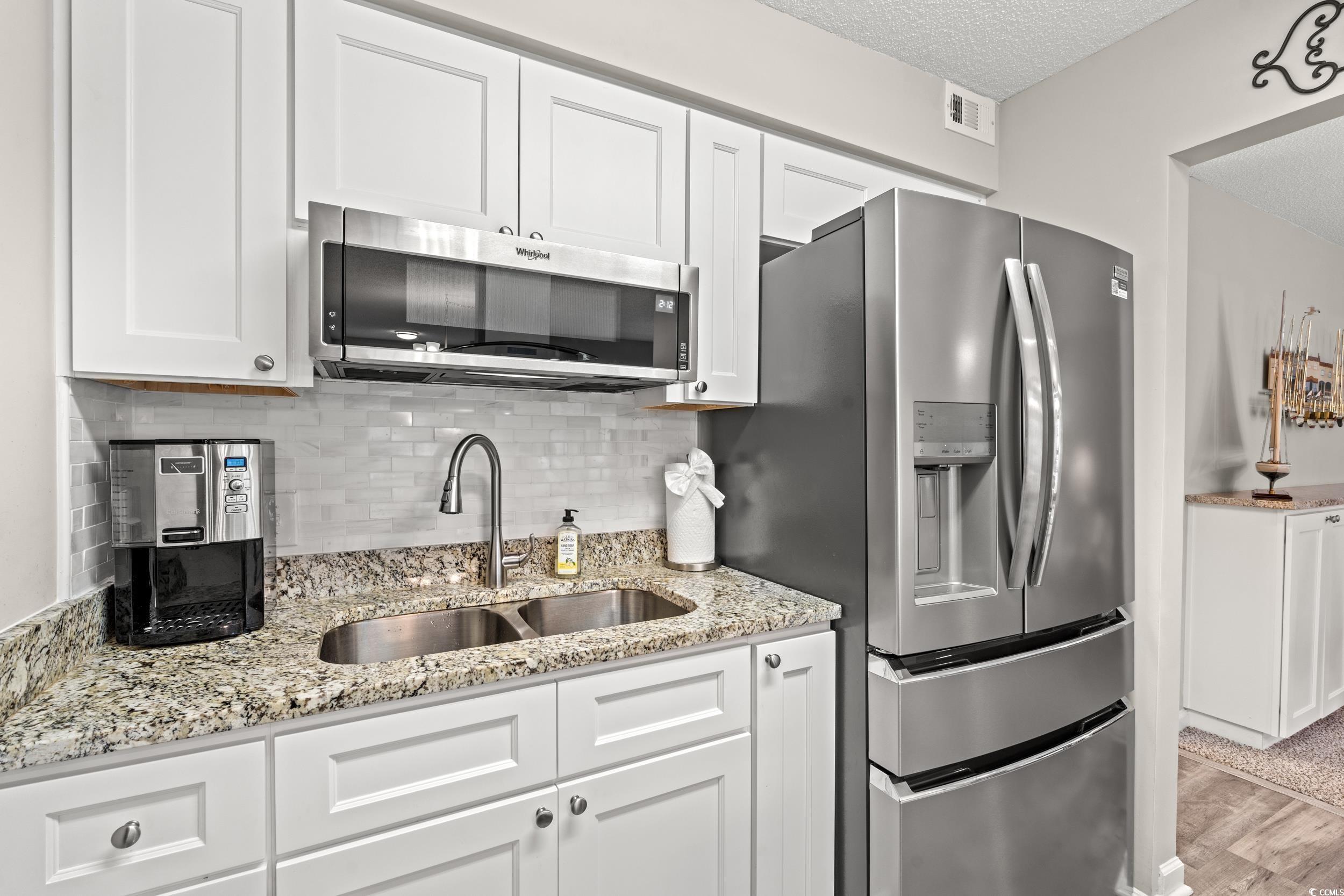 14 Laurel Street, Unit 14 Conway, SC 29526 - Photo 13 of 40 Kitchen with appliances with stainless steel finishes, backsplash, light stone counters, white cabinets, and a textured ceiling
