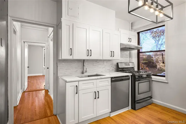 a kitchen with stainless steel appliances granite countertop a stove and white cabinets