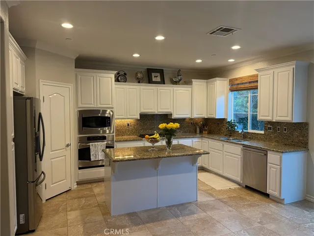 a kitchen with stainless steel appliances granite countertop a stove top oven a refrigerator a sink and dishwasher