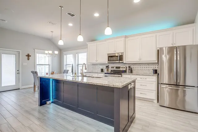 a kitchen with kitchen island granite countertop a sink cabinets and stainless steel appliances
