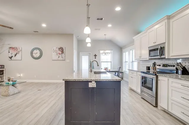 a open kitchen with stainless steel appliances granite countertop a stove and a wooden floors