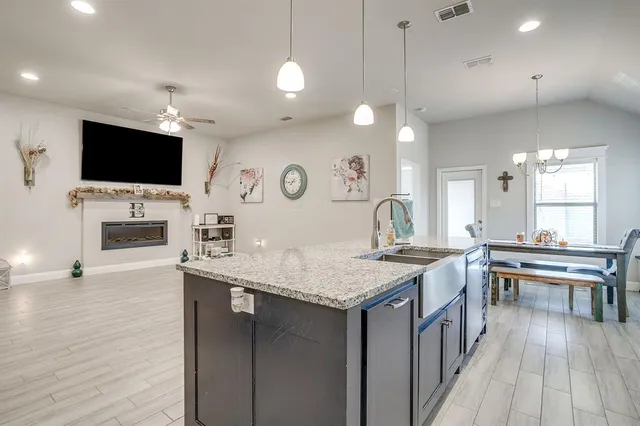 a large kitchen with stainless steel appliances kitchen island granite countertop a large stove a sink dishwasher and white cabinets with wooden floor