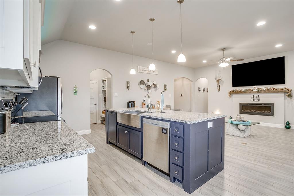940 Sam Street Springtown, TX 76082 - Photo 16 of 39 a large kitchen with stainless steel appliances kitchen island granite countertop a large stove a sink dishwasher and white cabinets with wooden floor