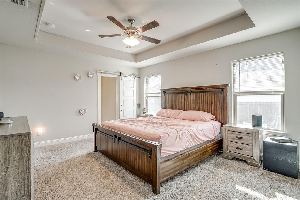 940 Sam Street Springtown, TX 76082 - Photo 21 of 39 a spacious bedroom with a bed and a chandelier