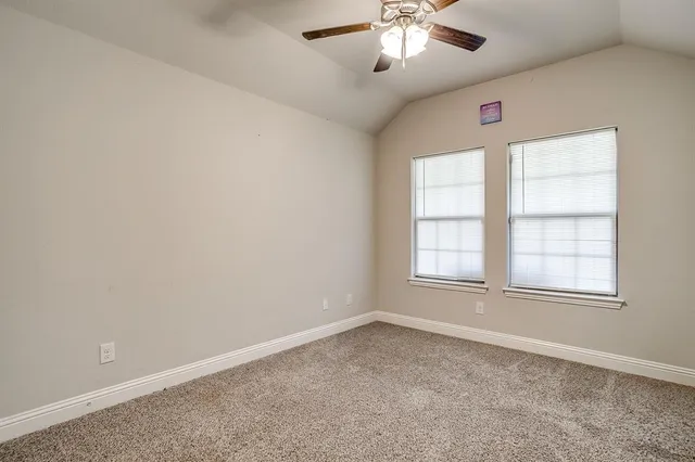 an empty room with chandelier fan and windows