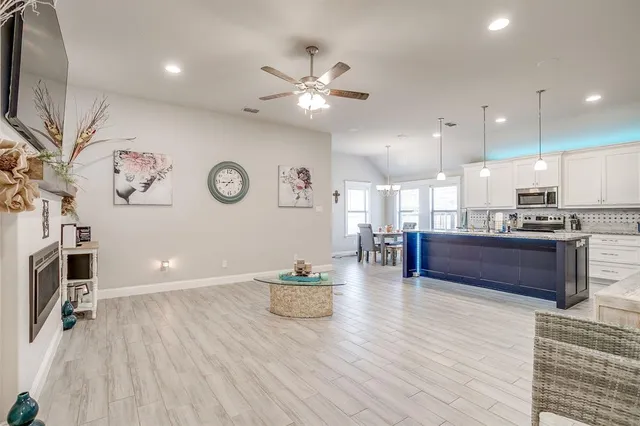 a living room with furniture a flat screen tv and kitchen view