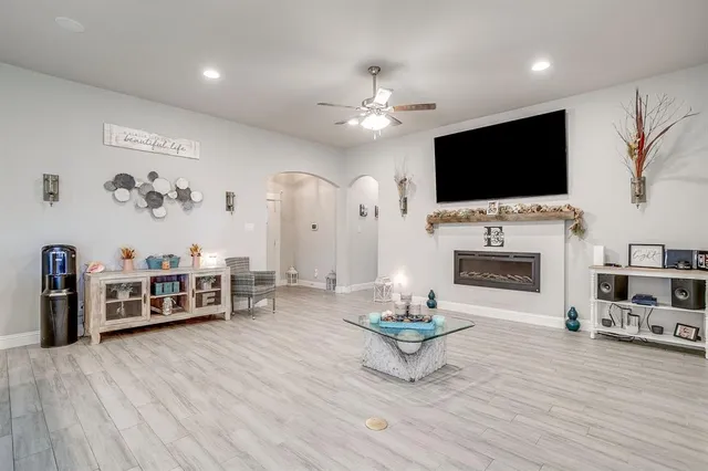 a living room with furniture kitchen view and a wooden floor