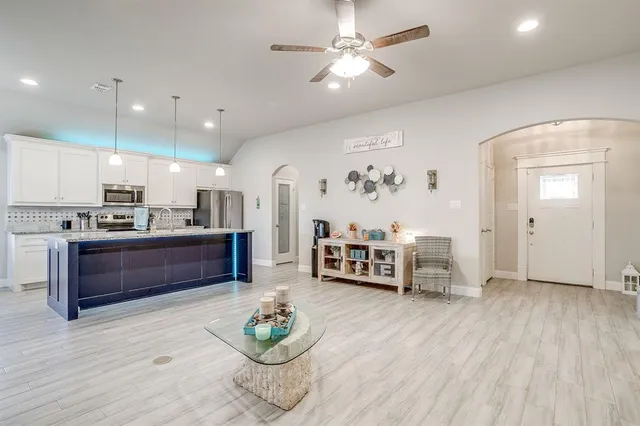 a kitchen with kitchen island granite countertop a sink cabinets and wooden floor
