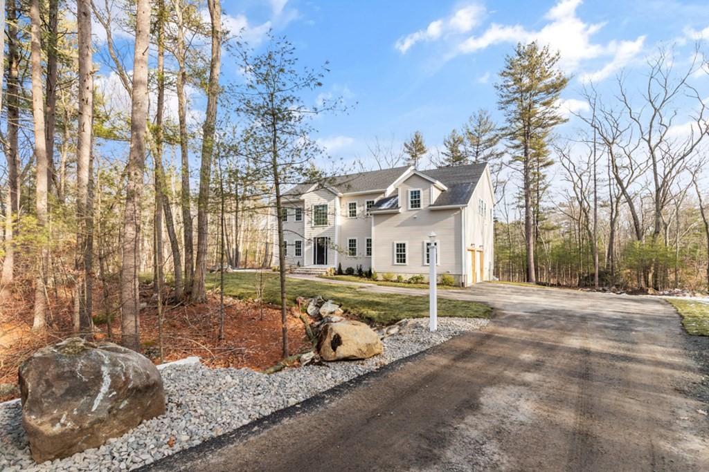 a front view of a house with a yard covered with snow and trees