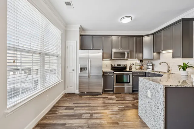 a kitchen with granite countertop a refrigerator and a stove top oven