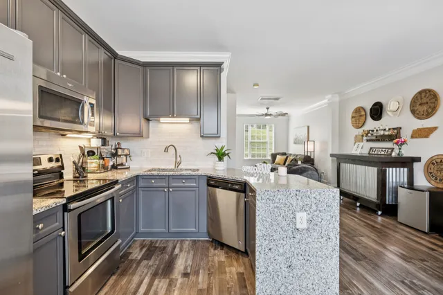 a kitchen with stainless steel appliances granite countertop a sink stove refrigerator and cabinets