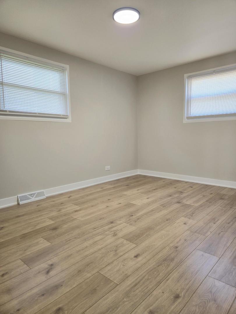 16536 Wolcott Avenue Markham, IL 60428 - Photo 9 of 18 a view of an empty room with wooden floor and a window