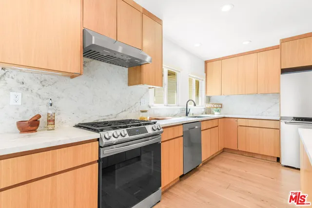 a kitchen with stainless steel appliances granite countertop a stove a sink a microwave a dining table and chairs