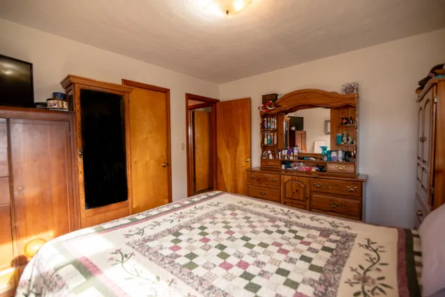 a bedroom with a bed and a large mirror on the dresser