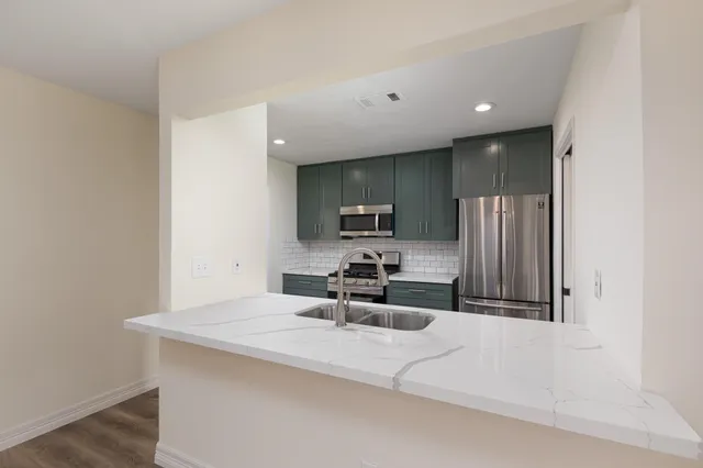 a kitchen with stainless steel appliances kitchen island granite countertop a stove and a sink