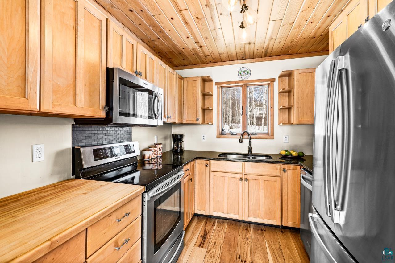 67 Snowshoe Trail Tofte, MN 55615 - Photo 23 of 42 Kitchen with stainless steel appliances, open shelves, light wood-style floors, light wood finish cabinets, and dark countertops