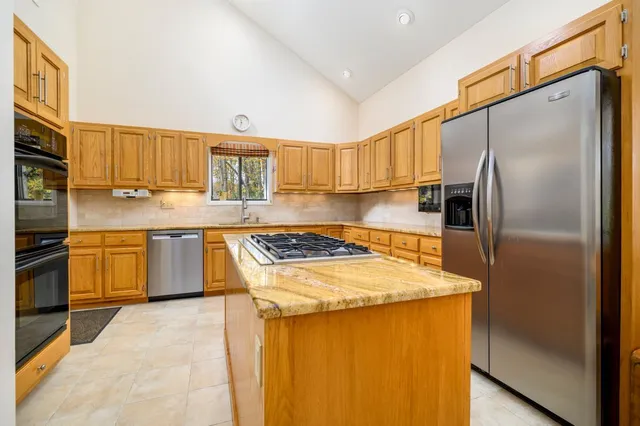 a kitchen with stainless steel appliances granite countertop a stove a refrigerator and a sink