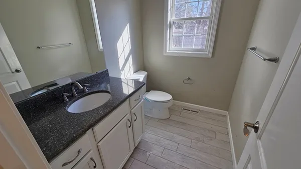 a bathroom with a granite countertop sink toilet and mirror
