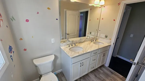 a bathroom with a granite countertop sink a toilet and a mirror