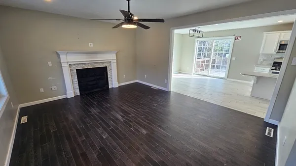 an empty room with wooden floor fireplace and windows