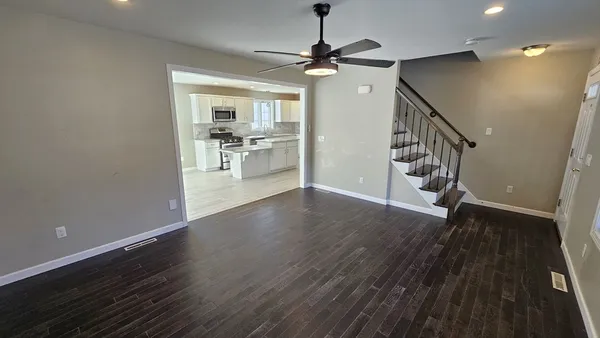 a view of a hallway with wooden floor and a kitchen