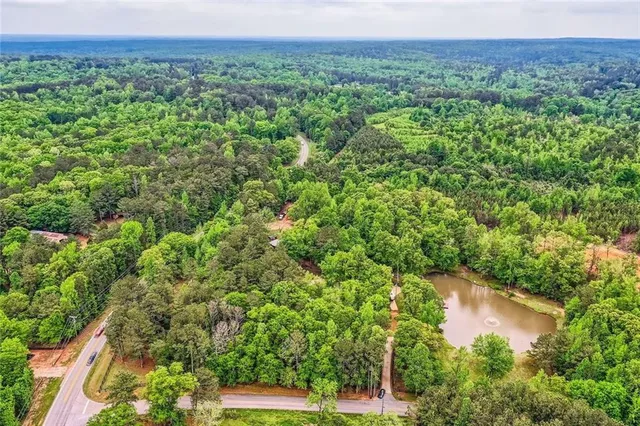 front view of a house with potted plants and large trees
