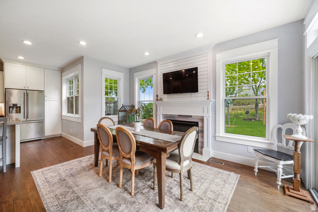357 South 320 W Street Lindon, UT 84042 - Photo 8 of 41 Open-concept dining area featuring wood-finish flooring, a white mantel fireplace with shiplap accent wall, and multiple windows with white trim