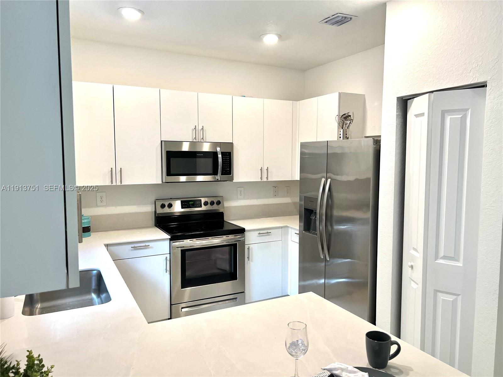 23250 Southwest 133rd Court Homestead, FL 33032 - Photo 3 of 31 a kitchen with stainless steel appliances granite countertop a stove a refrigerator and a microwave