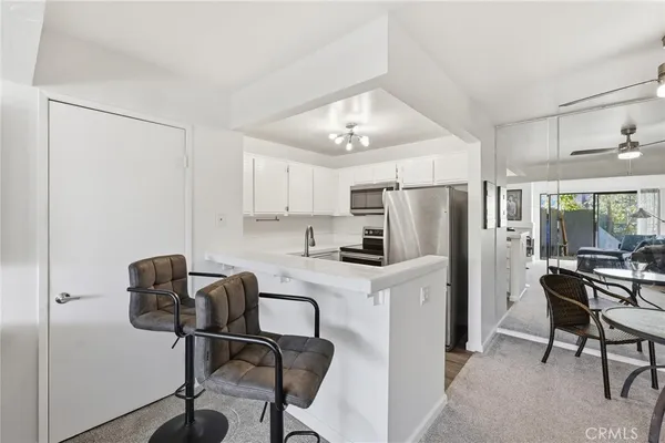 a kitchen with stainless steel appliances a refrigerator a stove a sink dishwasher and white cabinets with wooden floor