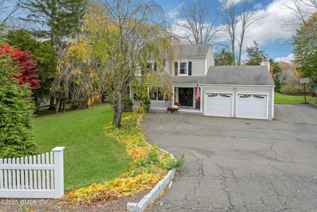 a view of a house with a small yard and large tree