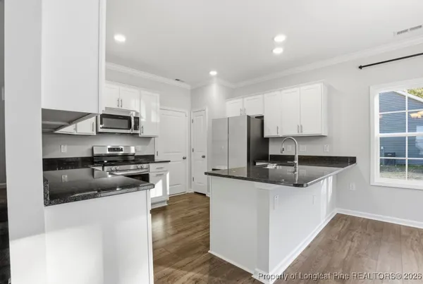 a kitchen with stainless steel appliances granite countertop a sink a stove a refrigerator a center island and cabinets