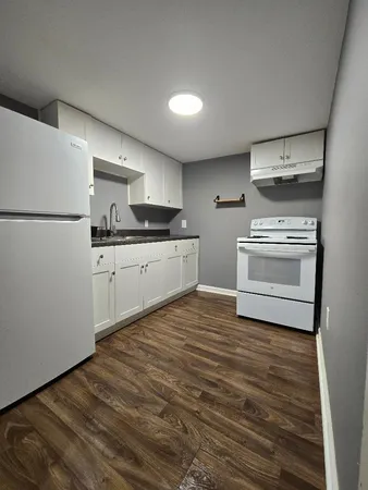 a kitchen with stainless steel appliances a stove top oven a refrigerator and white cabinets