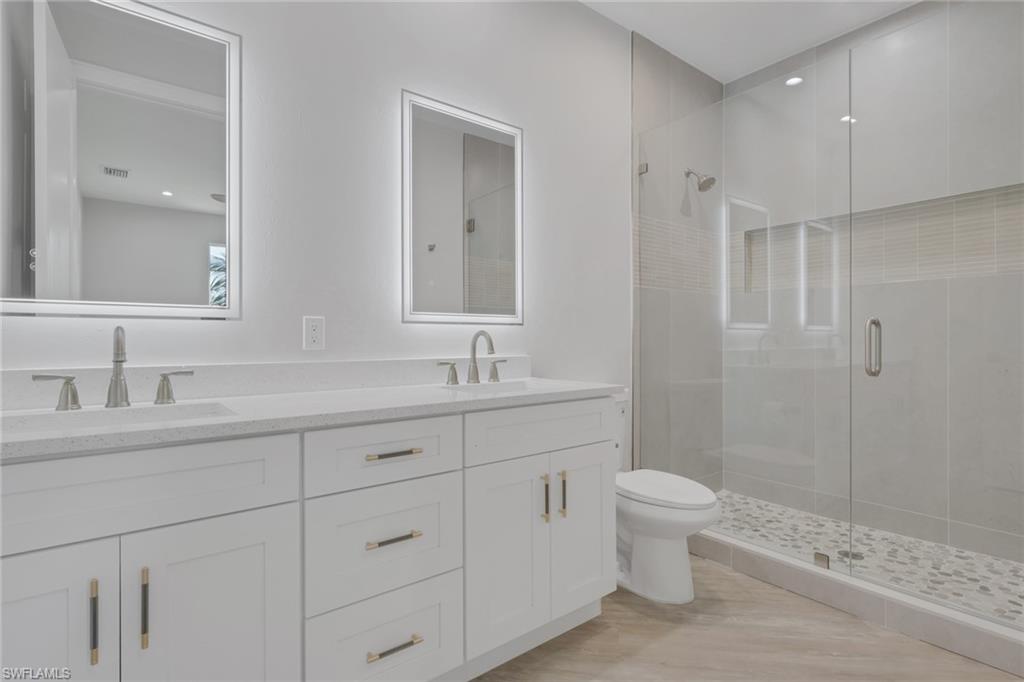 3500 Croton Road, Unit 101 Naples, FL 34104 - Photo 15 of 27 a bathroom with a double vanity sink toilet and shower