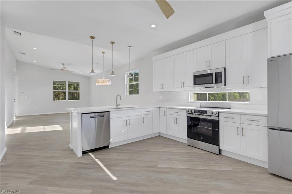 3500 Croton Road, Unit 101 Naples, FL 34104 - Photo 7 of 27 a large kitchen with cabinets wooden floor and stainless steel appliances
