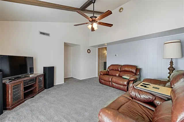 a living room with furniture a ceiling fan and a flat screen tv
