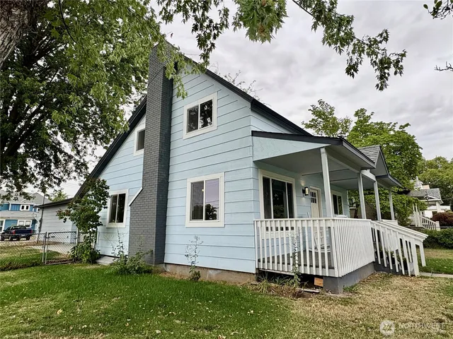 a backyard of a house with plants and large tree