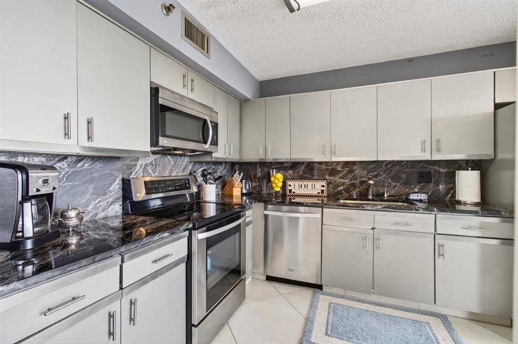 7145 Promenade Drive, Unit 602 Boca Raton, FL 33433 - Photo 30 of 90 a kitchen with granite countertop white cabinets stainless steel appliances and a sink