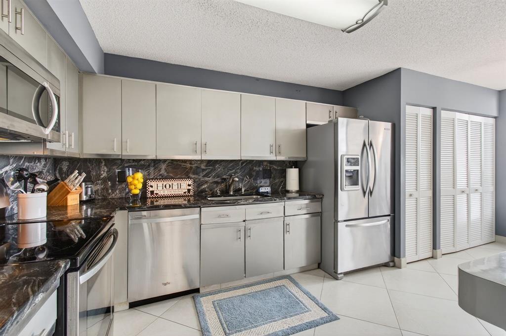 7145 Promenade Drive, Unit 602 Boca Raton, FL 33433 - Photo 31 of 90 a kitchen with stainless steel appliances granite countertop a refrigerator sink and cabinets