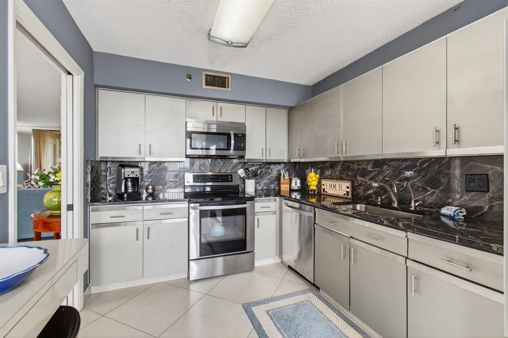7145 Promenade Drive, Unit 602 Boca Raton, FL 33433 - Photo 32 of 90 a kitchen with stainless steel appliances granite countertop a sink a stove top oven a counter space and cabinets