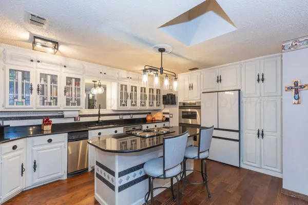 a kitchen with stainless steel appliances granite countertop a sink stove and cabinets